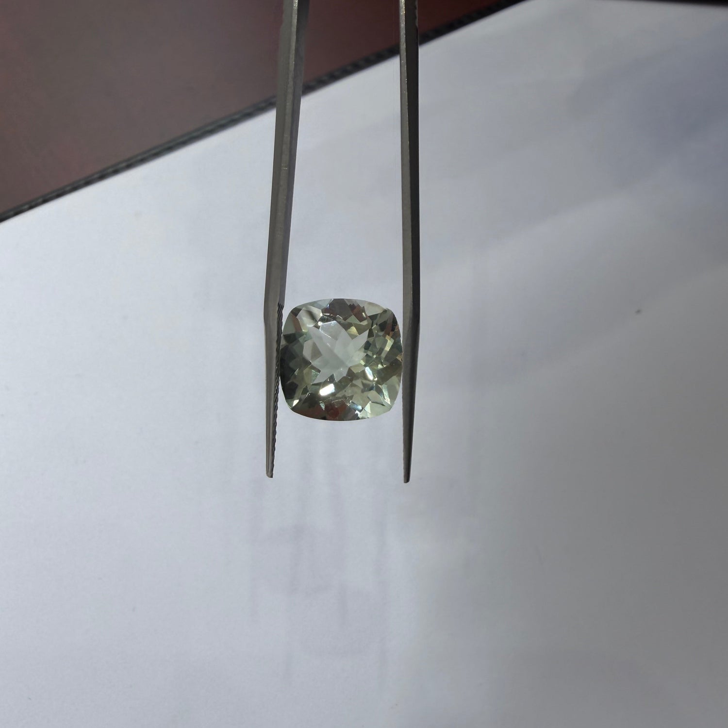 Diamond held between tweezers on a white background