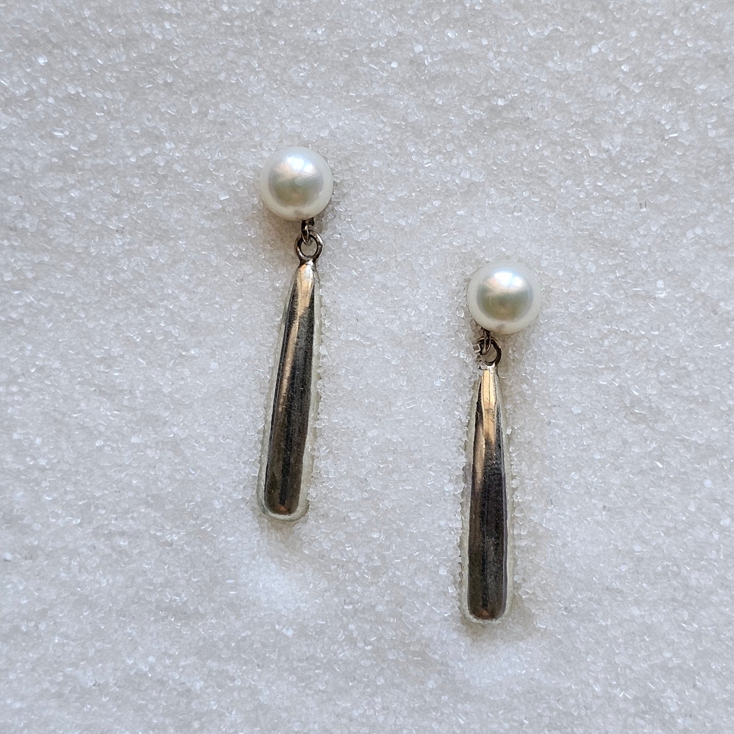 Pair of pearl earrings on a textured white surface