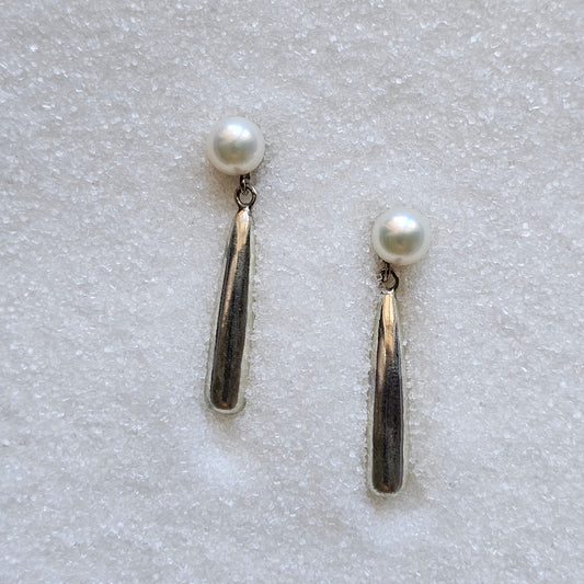 Pair of pearl earrings on a textured white surface